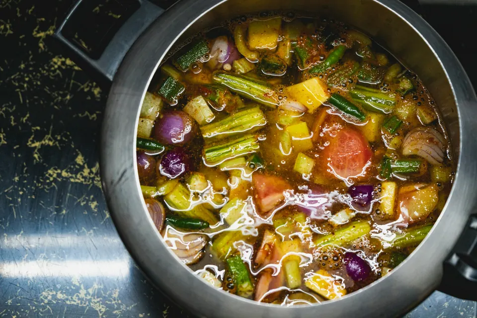 A pot of vegetable soup with green beans, tomatoes and peppers simmering on the stove